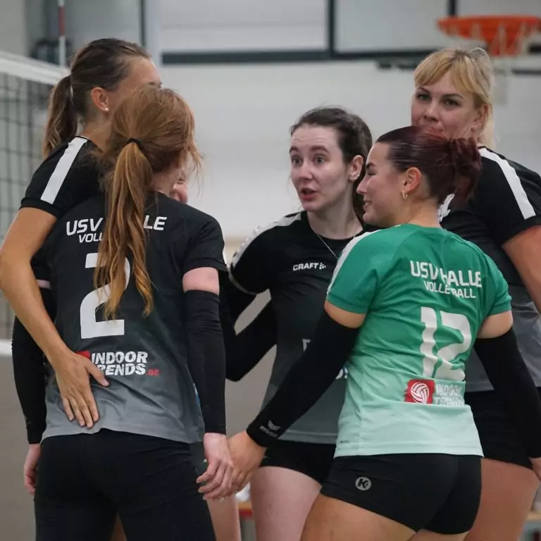 Eine Volleyballmannschaft steht auf dem Feld in einem Kreis zusammen und bespricht sich. USV Halle Volleyball Damen 2